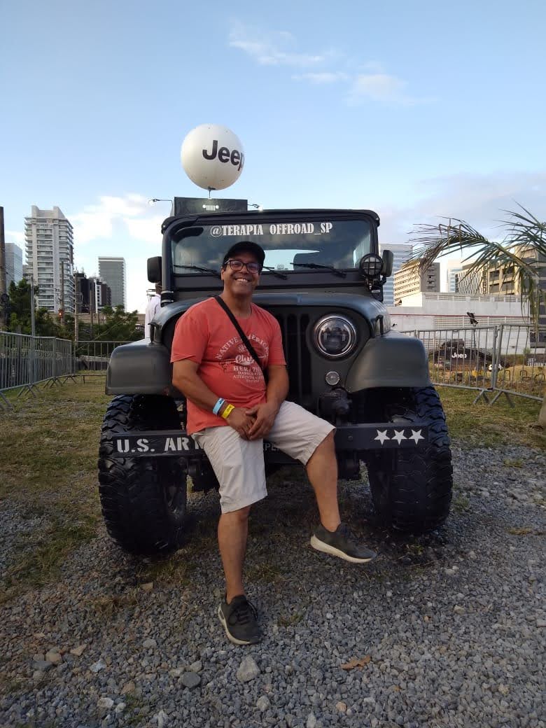 Ricardo Santos sentado na frente de um Jeep em evento automotivo